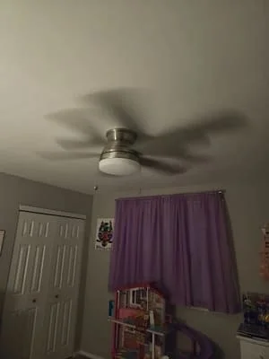 Brushed nickel ceiling fan with dark blades mounted to white drywall ceiling
