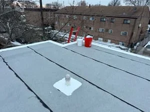 Light-colored flat roof membrane with seams and flashing on residential building