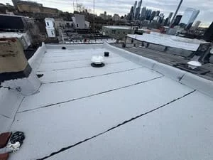 White membrane flat roof with sealed seams and roof penetrations on commercial building