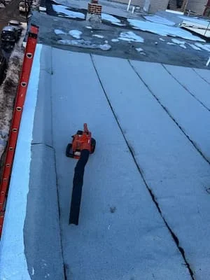 Technician sealing roofing membrane seams on large commercial flat roof installation