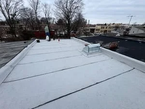 White membrane flat roof with seam lines, HVAC unit, and roof penetrations on commercial building