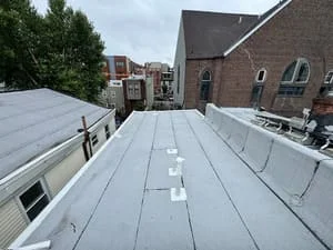 Gray flat roof membrane with seams and edge trim on residential building