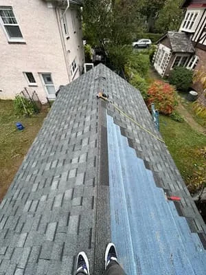 New gray asphalt shingles installed on pitched residential roof with ridge cap detail