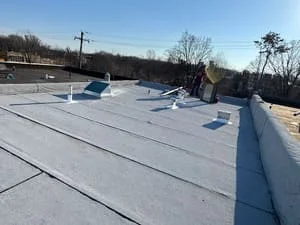 Flat roof with white membrane, roof vents, and perimeter curbing on commercial building