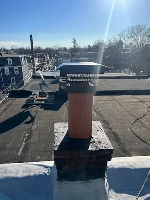 Metal pipe boot with flashing and sealant on flat roof surface